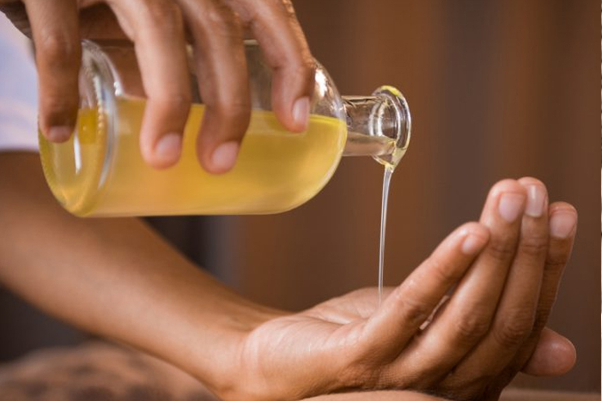 A massage specialist at Glamour Spa Islamabad pouring aromatic oils into her hands, preparing for a rejuvenating oil massage therapy session for a client.